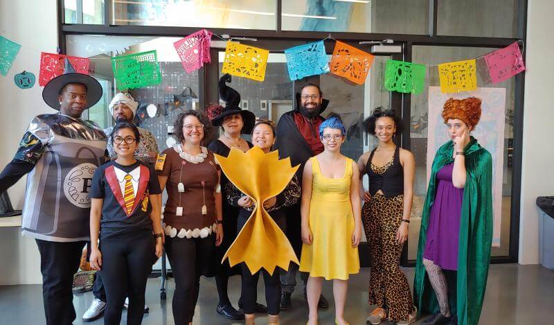 A multi-racial group of people in Halloween costumes pose