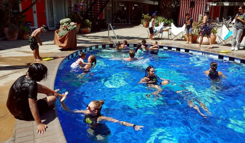 A group of kids and instructors swim in the Phoenix Hotel pool 