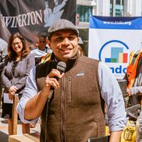 Maurilio León holds a mic in front of a tndc logo