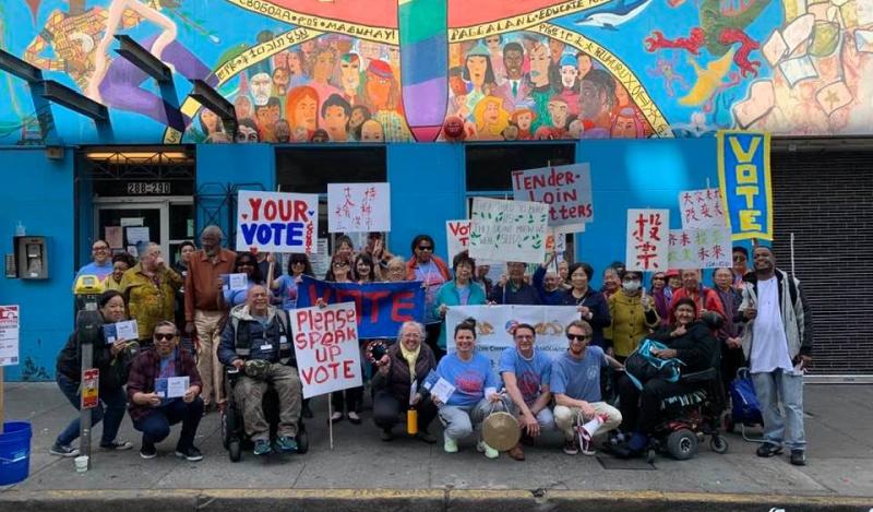 A multi-racial group gather with voting signs