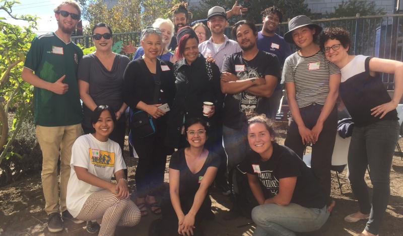 A multi-racial group gathers together for a photo in a garden