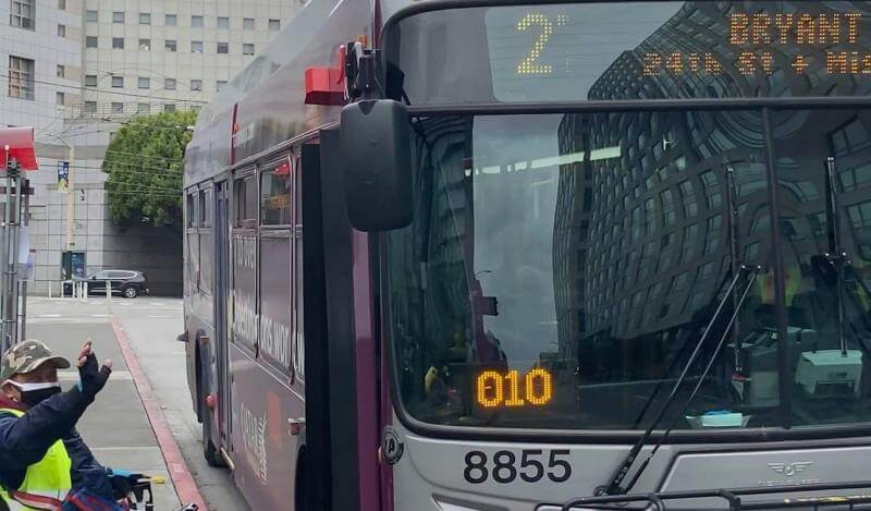 A TL activist in a wheelchair waves as he gets on the Muni 27