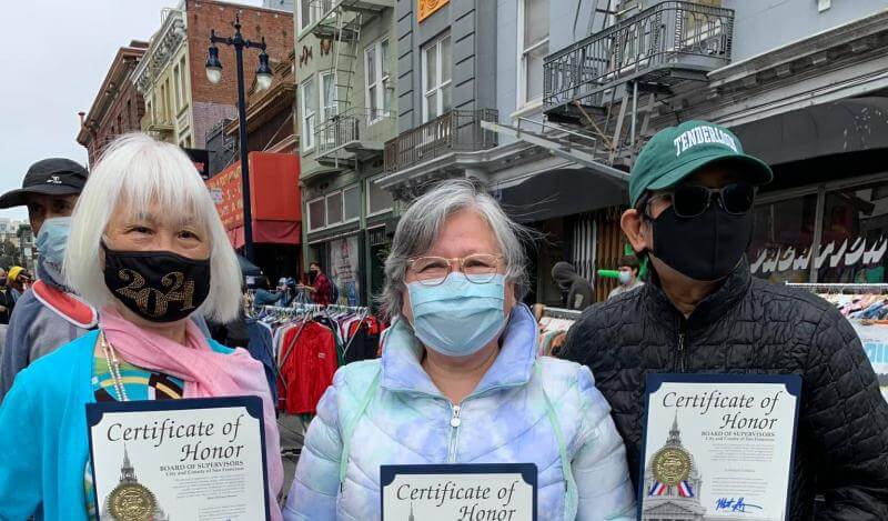Three AAPI activists wearing face masks pose with Certificates of Honor