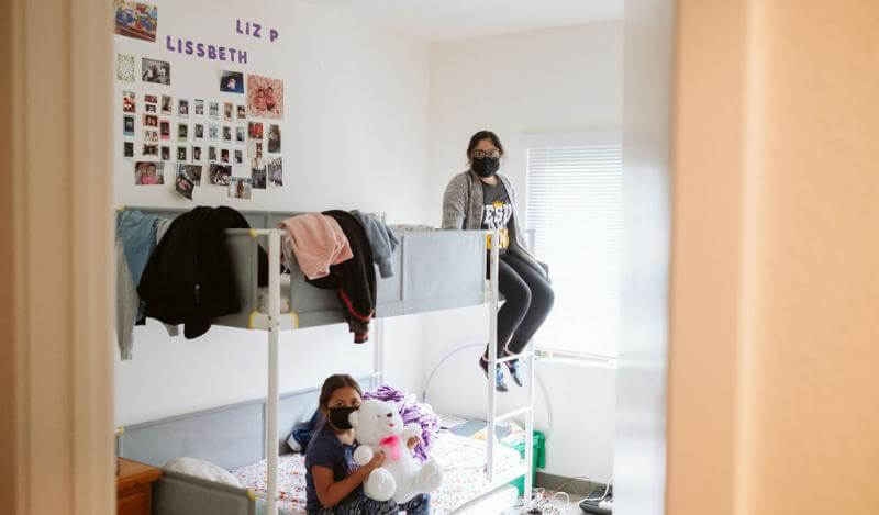 Two young girls sit on their bunk bed