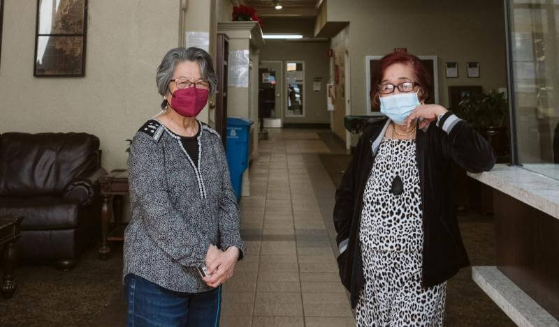 •An older Filipina with red hair stands in the lobby with her social worker