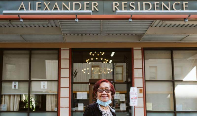 An older Filipina with red hair stands outside the Alexander Residence 