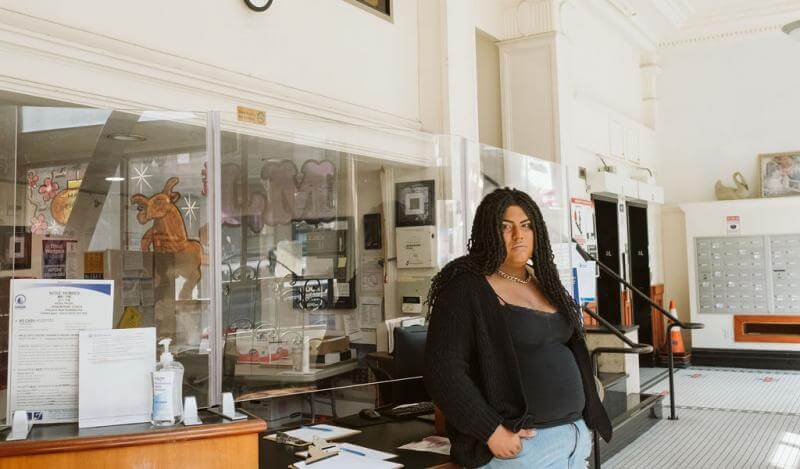 A woman in a black shirt stands in the Ambassador Hotel lobby