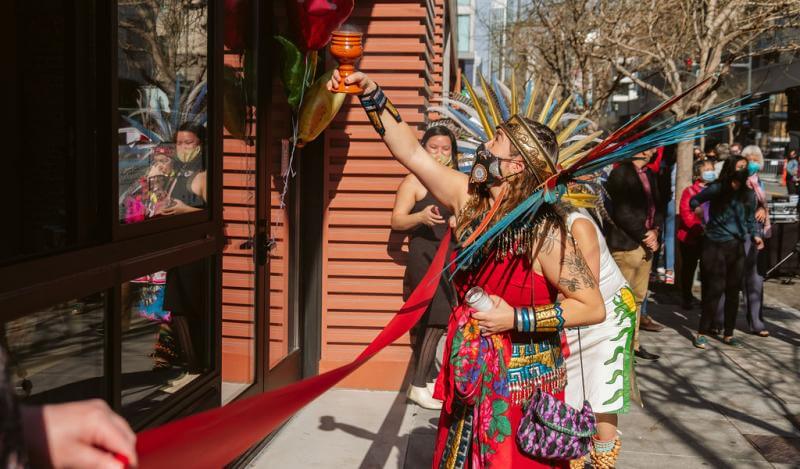 an Aztec dancer blesses the front door of a food pantry 