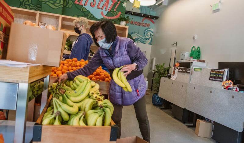 Staff members unpack bananas and oranges at Kain Na