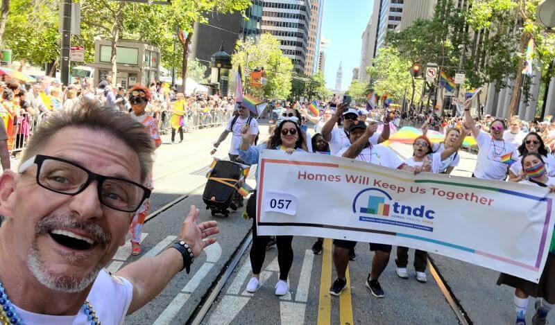 A diverse group cheers with a TNDC Pride Banner