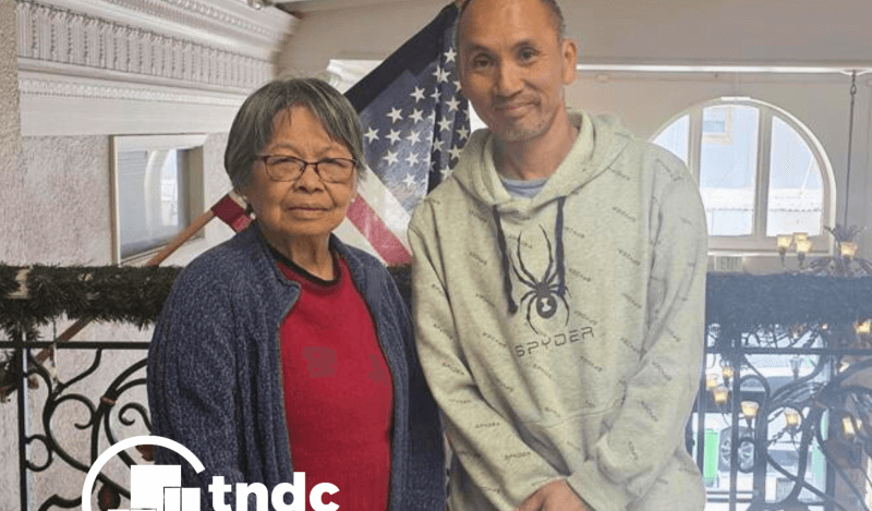 Paul and betty pose in front of american flag
