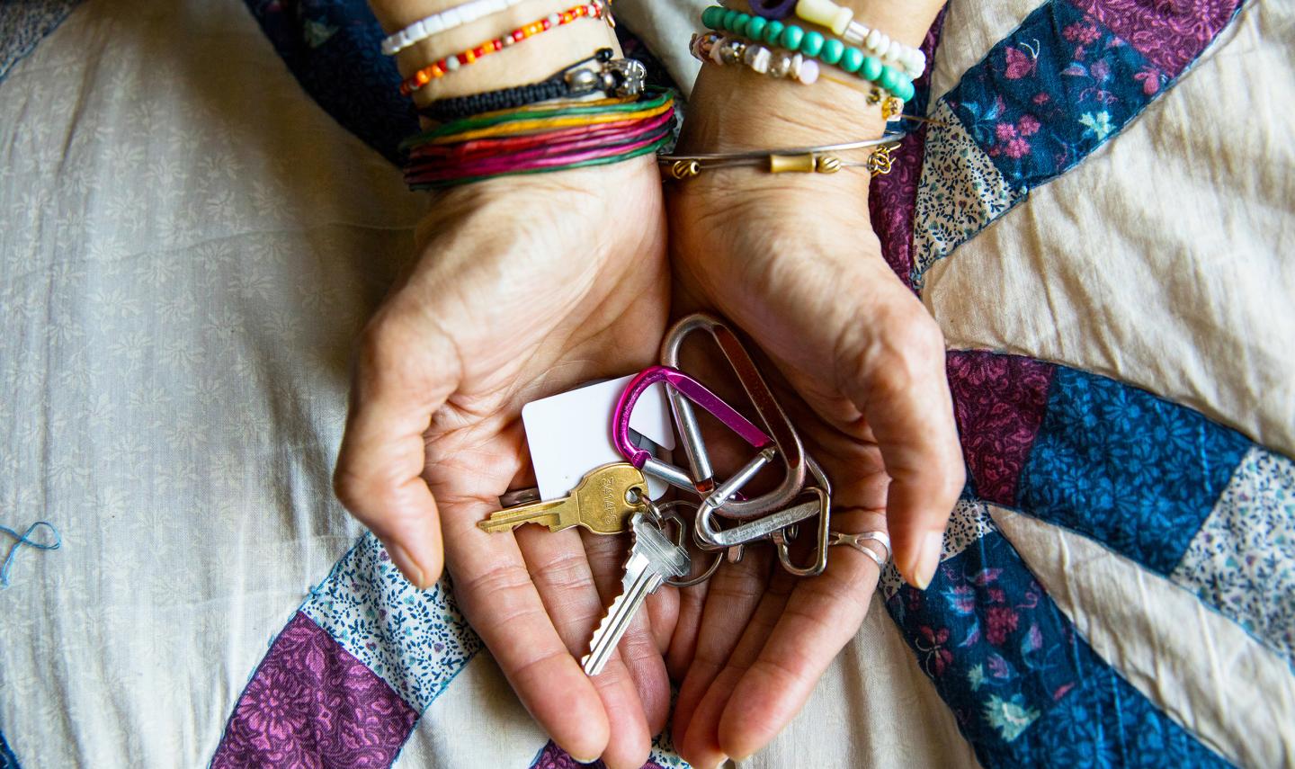 Hands cradle colorful keys above a quilt pattern