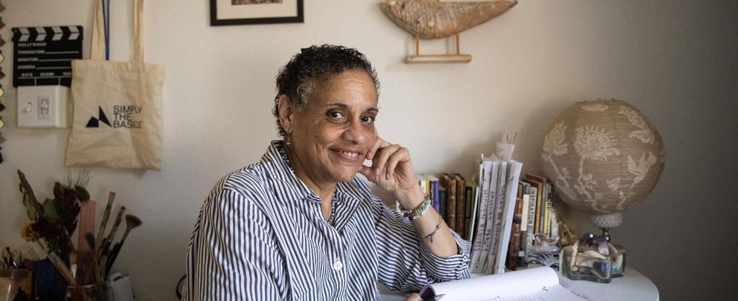 Black woman sits content at desk with journal and nautical theme behind her