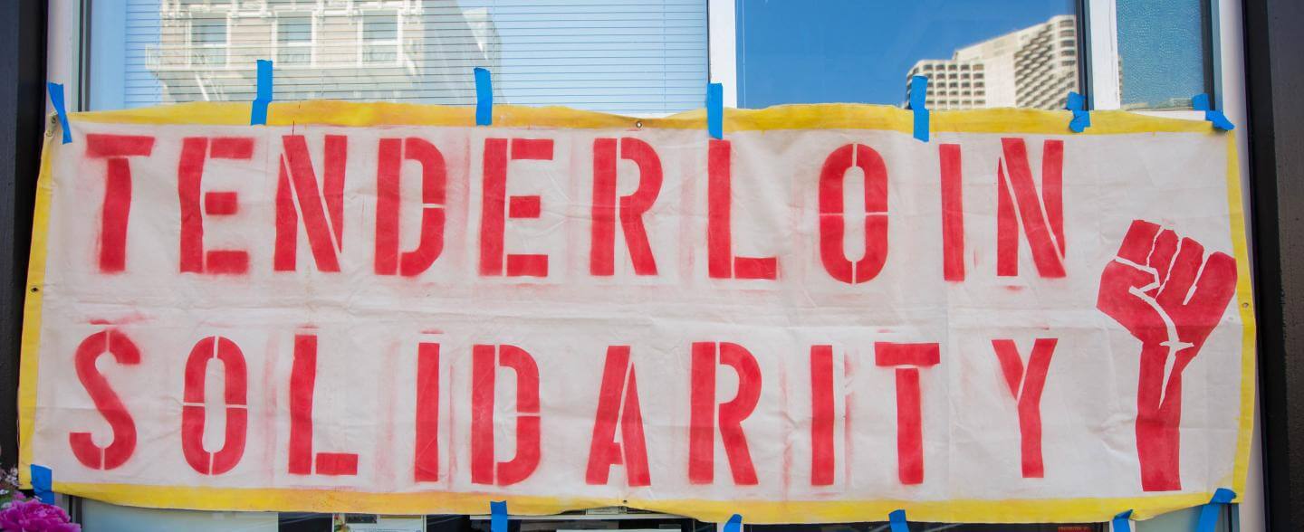 Handmade sign reads "Tenderloin Solidarity" with a raised fist