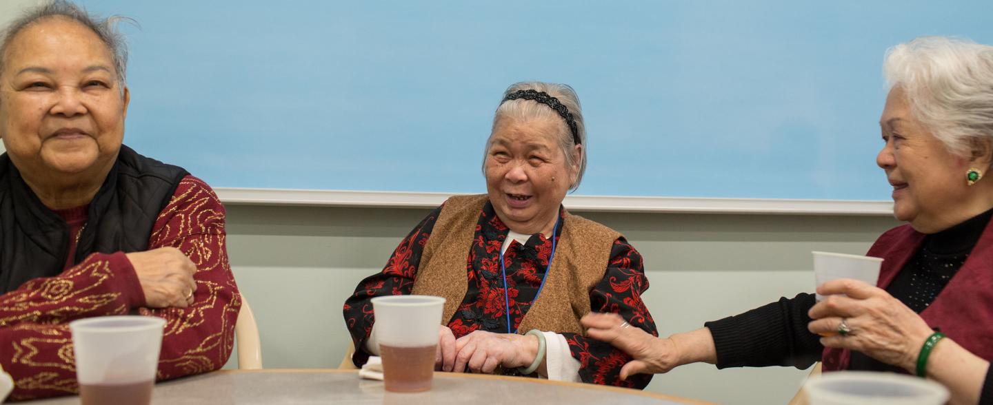 three asian women smile at a table with tea