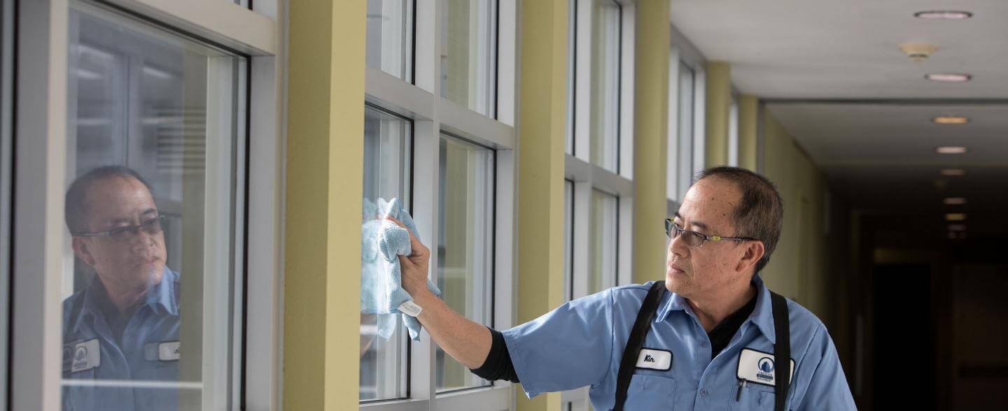 an asian custodian is cleaning building windows