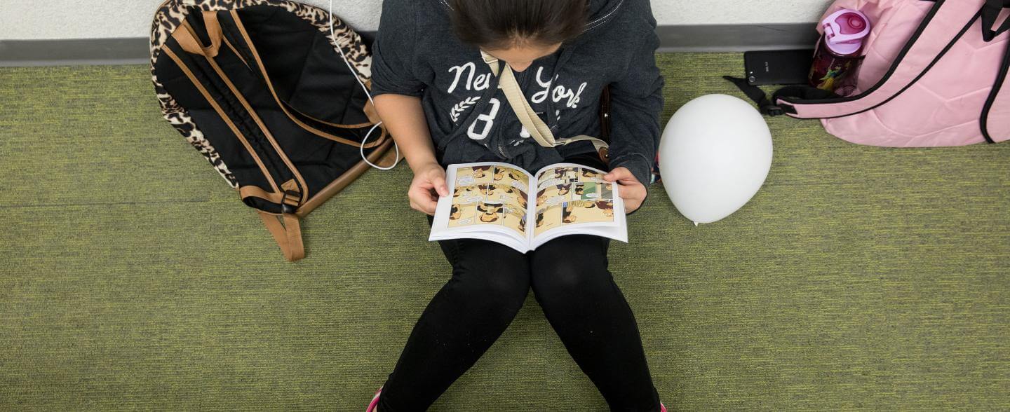 Young girl sits on the floor with her head down reading