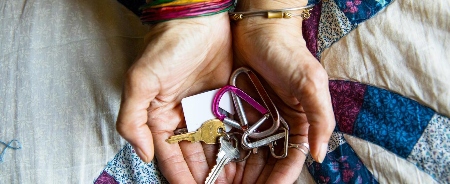 Hands cradle colorful keys above a quilt pattern