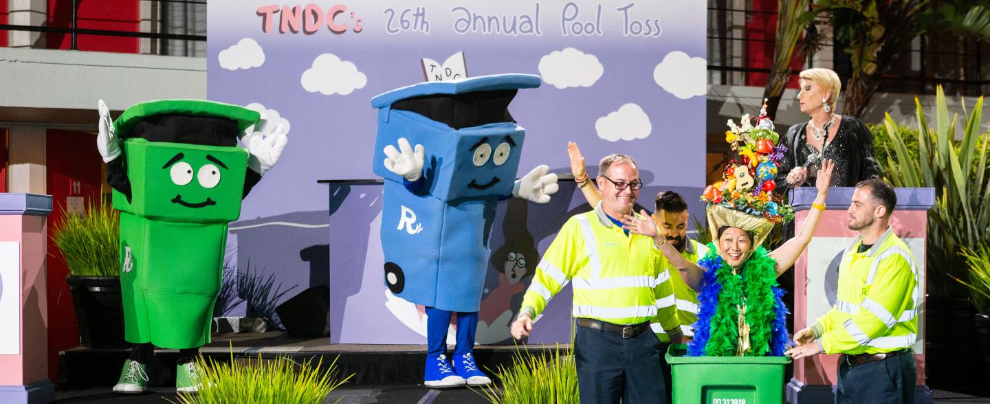 An Asian woman jumps out of recycling can on stage