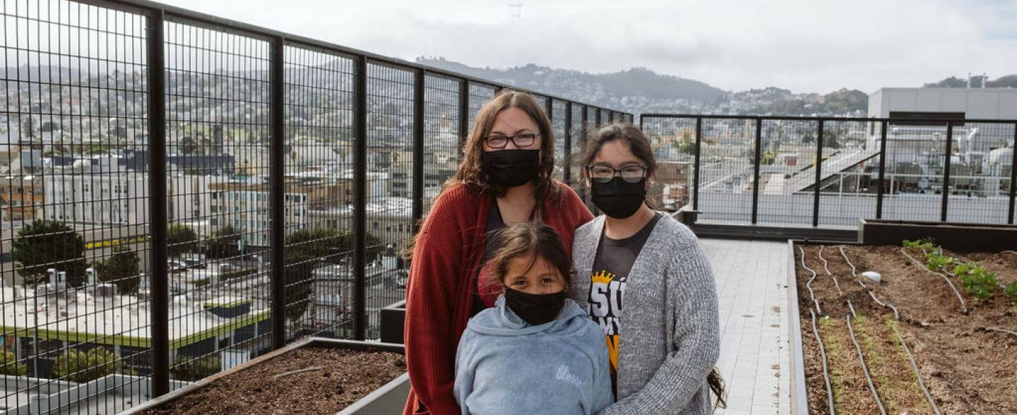 A mother and her two daughters stand on the rooftop of Casa Adelante -2828 16th Street