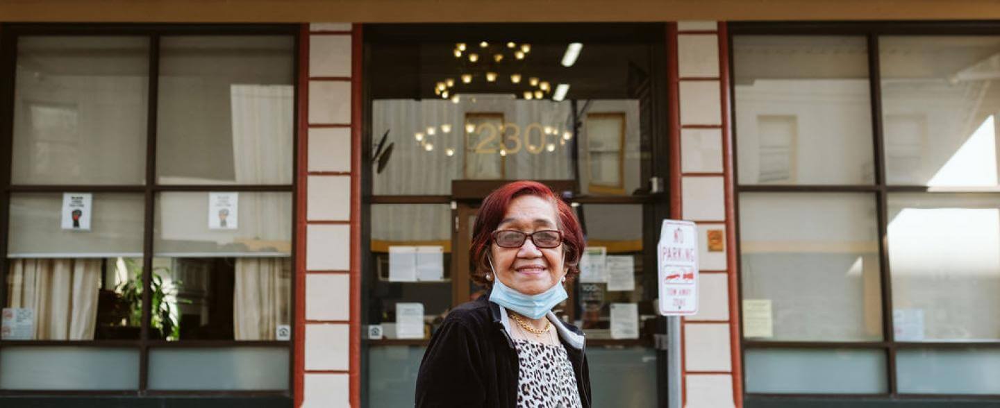 An older Filipina with red hair stands outside the Alexander Residence 