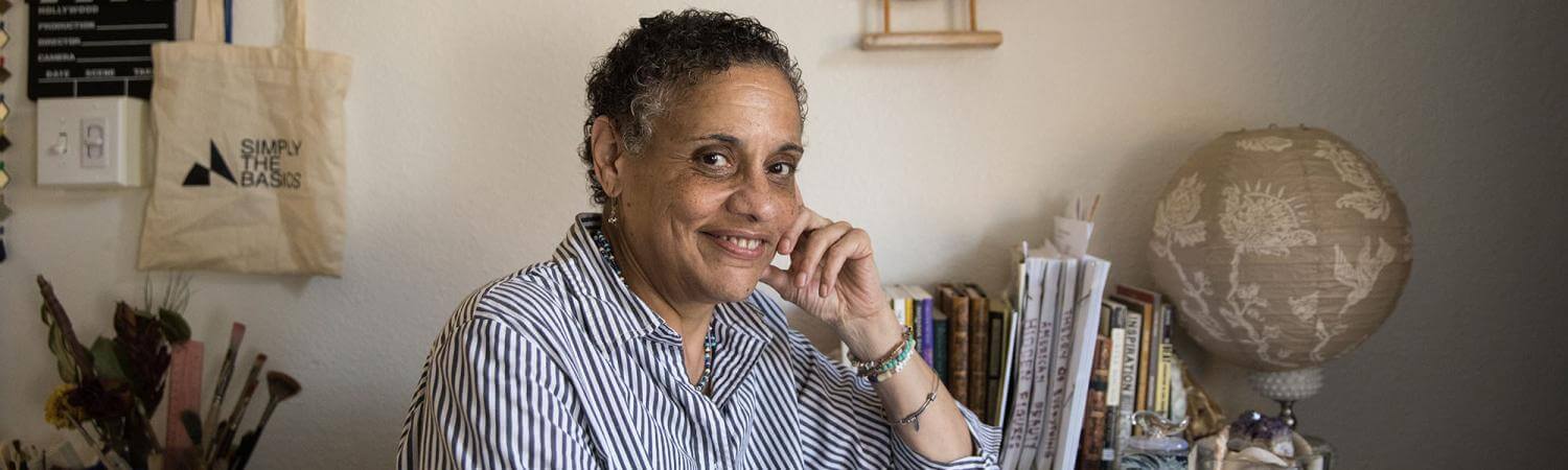Black woman sits content at desk with journal and nautical theme behind her