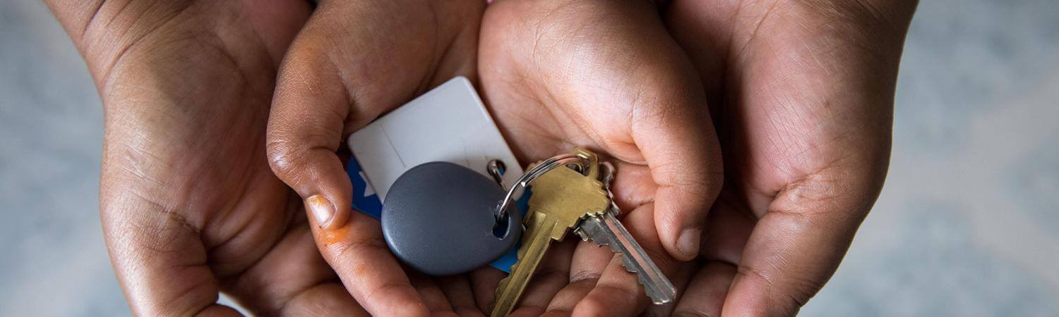 A Black mother's hands cradle child hands with house keys