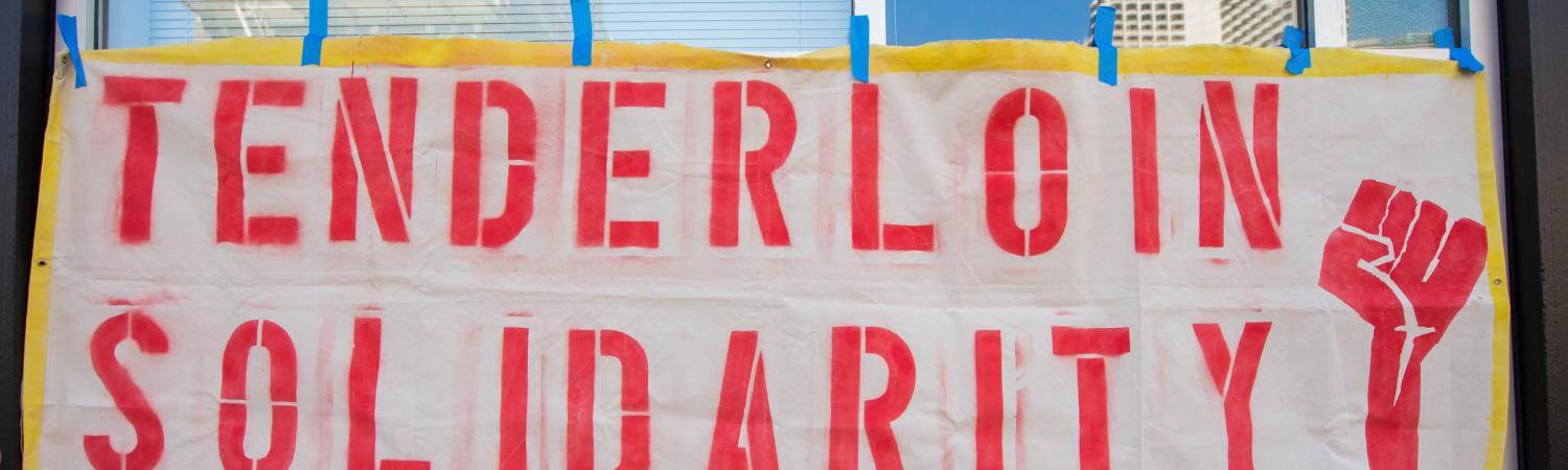 Handmade sign reads "Tenderloin Solidarity" with a raised fist