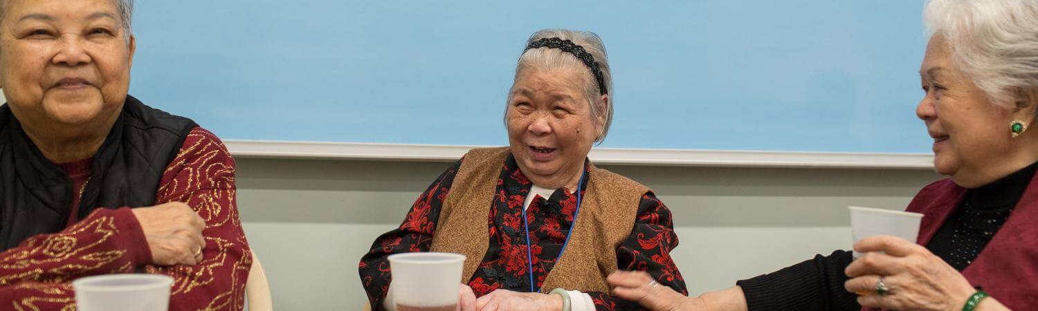 three asian women smile at a table with tea