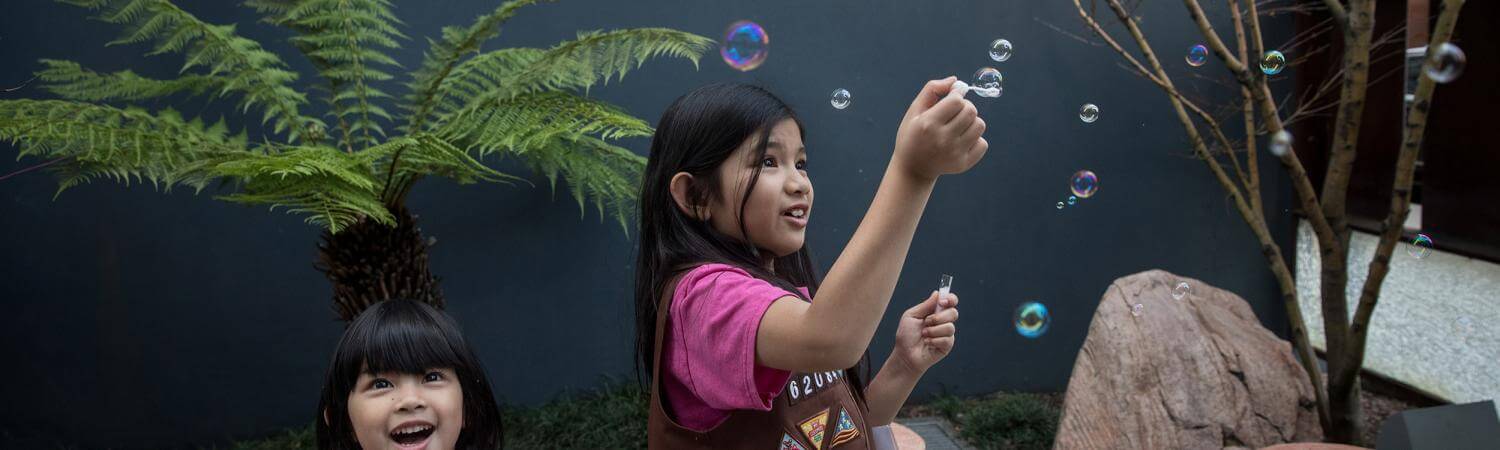 two asian-american sisters play with bubbles in a courtyard