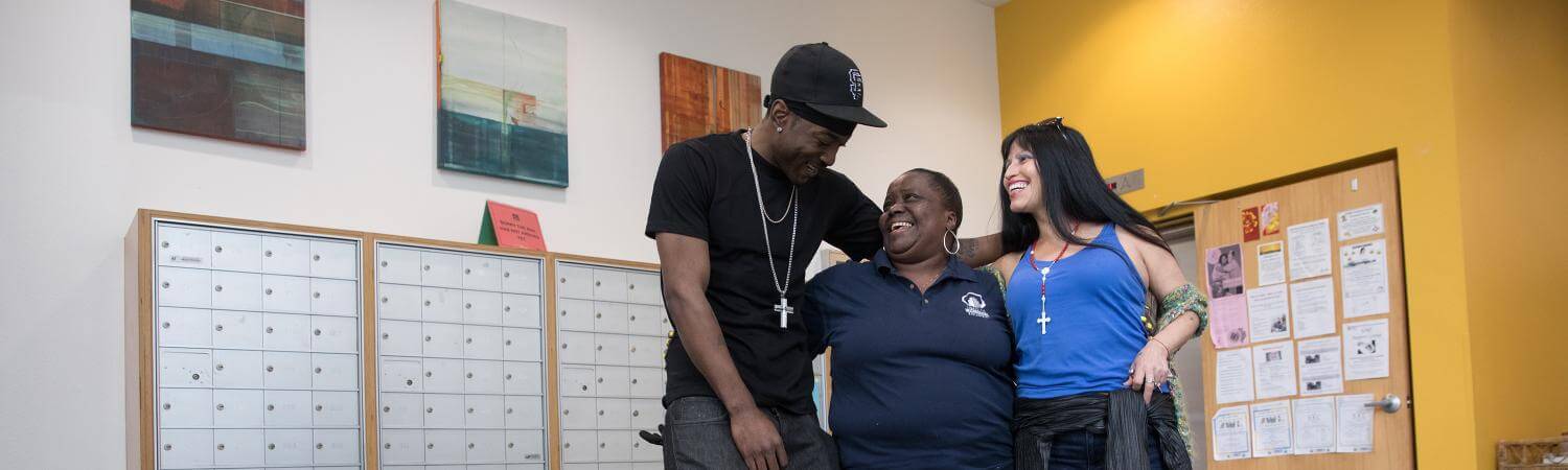 A multi-racial group of tenants and staff laugh together