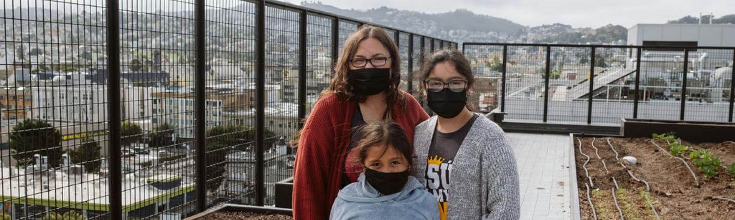 A mother and her two daughters stand on the rooftop of Casa Adelante -2828 16th Street