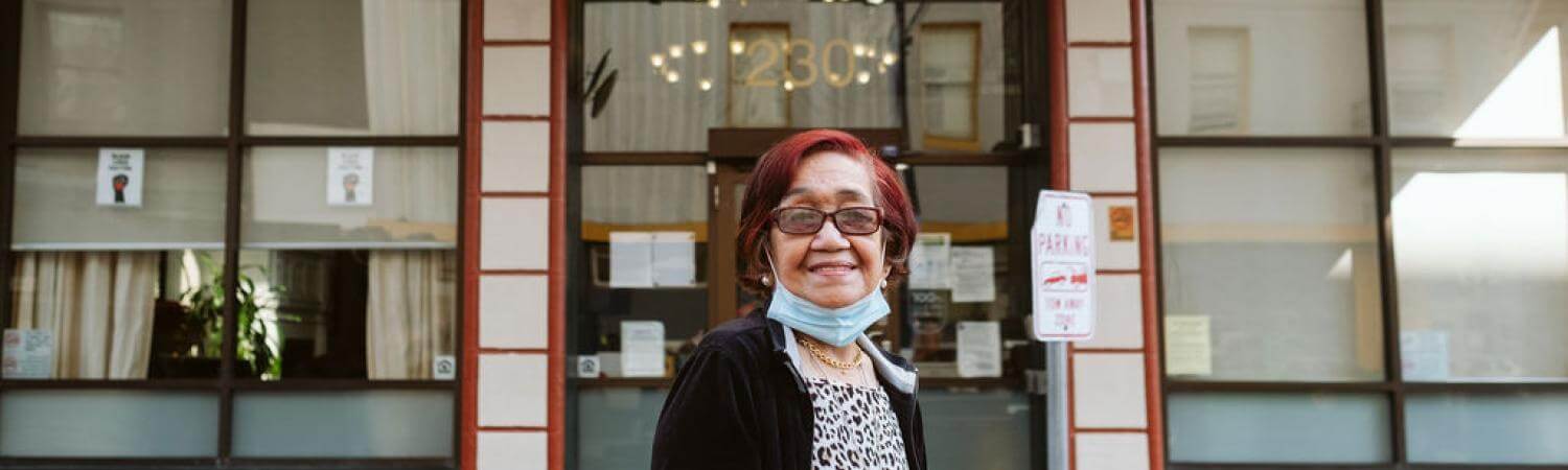 An older Filipina with red hair stands outside the Alexander Residence 