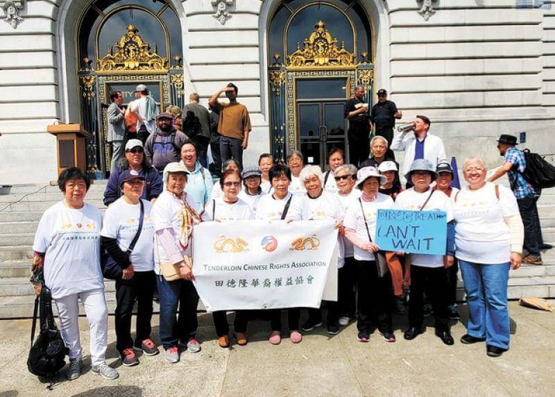 A group of people stand outside City Hall with a Chinese Rights Association sign