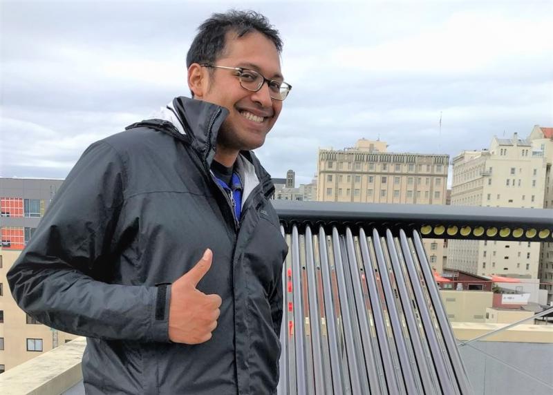 Ketan stands in front of solar panels
