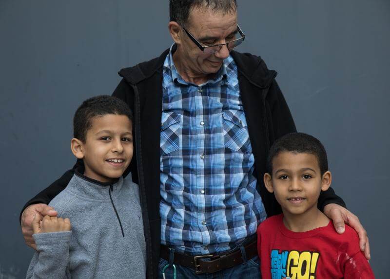 A grandfather hugs his two grandsons