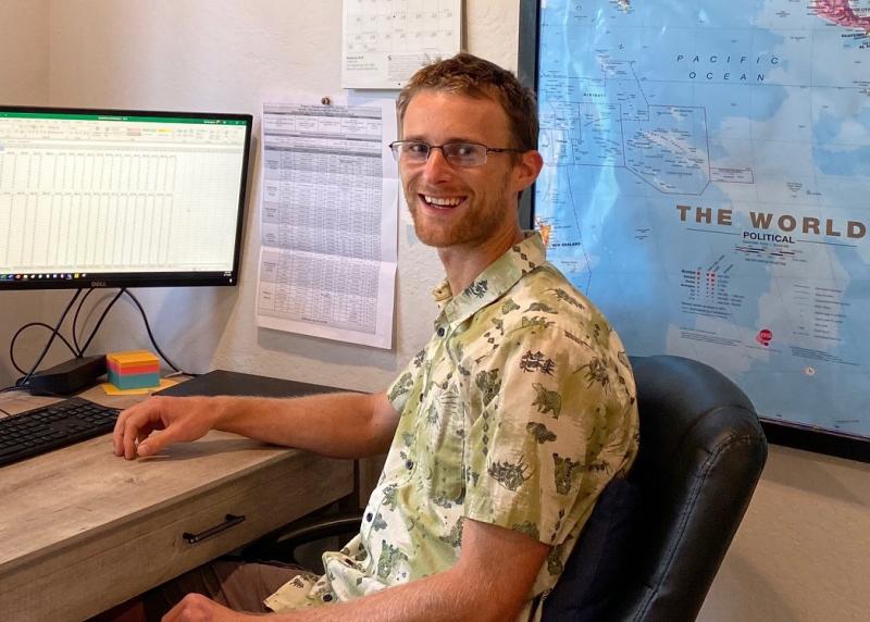 Tom sits at a desk working