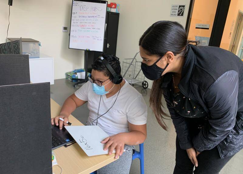 TASP staff member assists a kid with homework in a learning hub