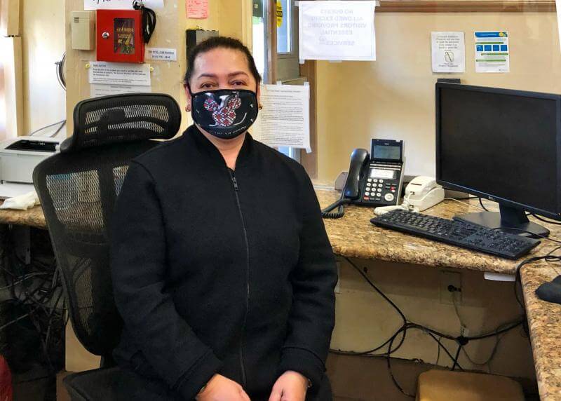 A woman wearing black sits on an office chair at a front desk in the Ritz Hotel