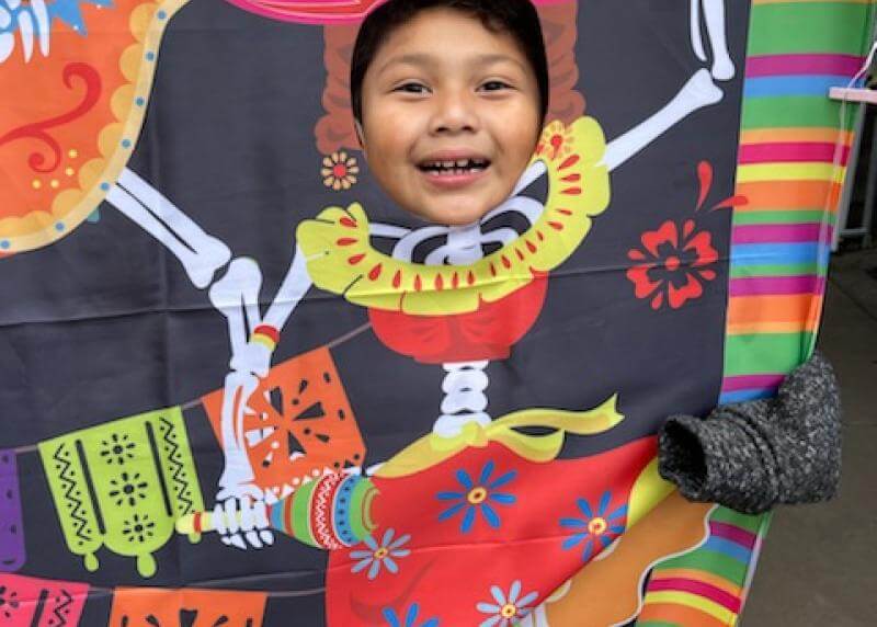 A child puts their head through a dia de los muertos photo stand-in