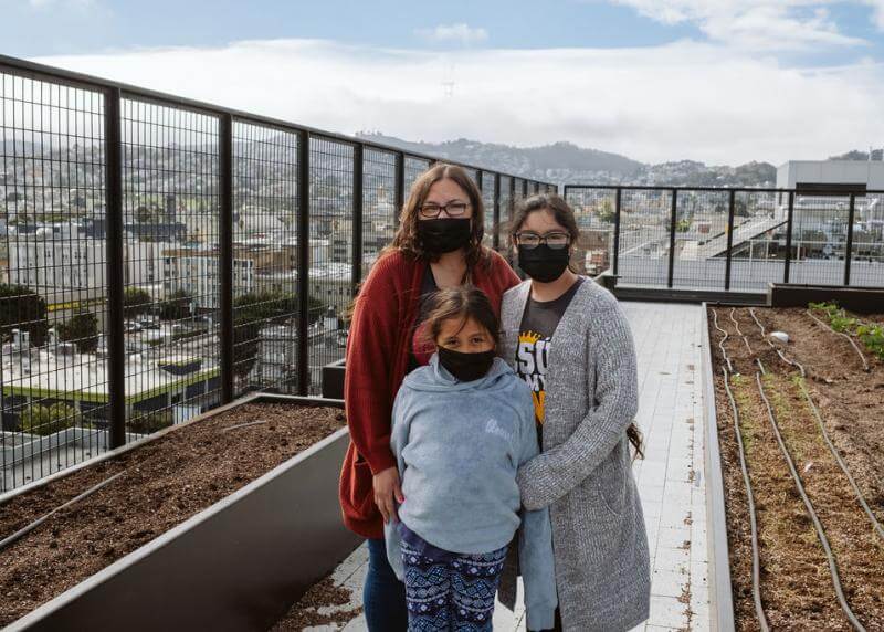 A mother and her two daughters stand on the rooftop of Casa Adelante -2828 16th Street