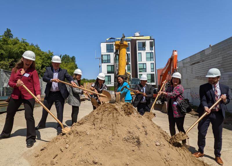 Group shovels dirt on a construction site in celebratory pos