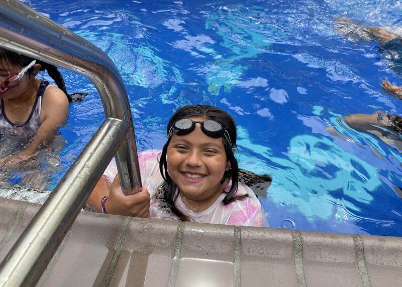 Young kid smiles from a pool