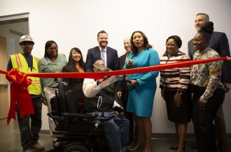 A multi-racial group including Mayor London Breed cut a bright red ribbon