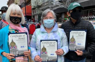 Three AAPI activists wearing face masks pose with Certificates of Honor
