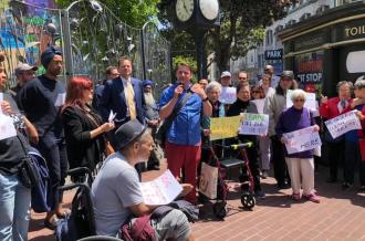 A diverse group of Tenderloin residents stand out sign with protest signs about safety