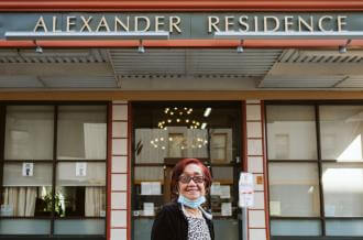 An older Filipina with red hair stands outside the Alexander Residence