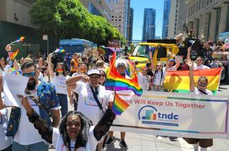 A diverse group in rainbow cheers at SF pride