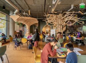 Kids and tutors gather at tables in a room with fun whimsical art 