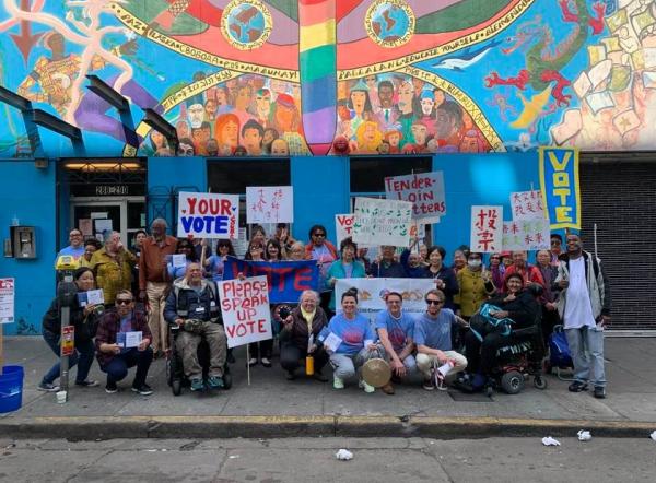 A multi-racial group gather with voting signs